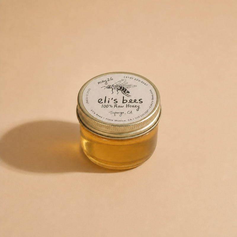 Eli's Bees raw honey in a small glass jar with a gold lid