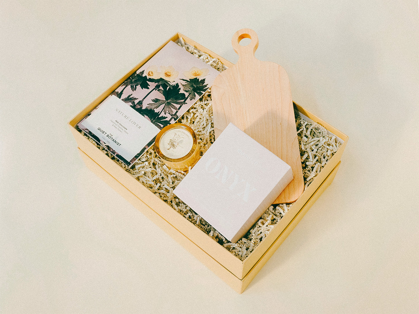 Giftbox with products for the home including a cutting board, artisan coffee, candle, and specialty chocolate.