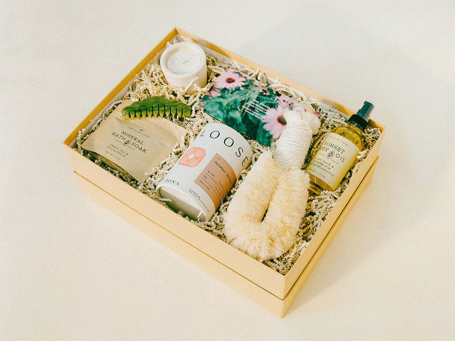 Gift box of relaxing bath products, chocolate, tea, and a candle.